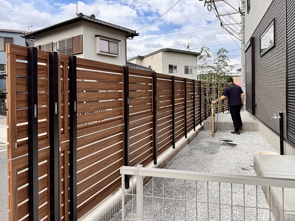 木目調の目隠しフェンスが設置された建物脇の通路